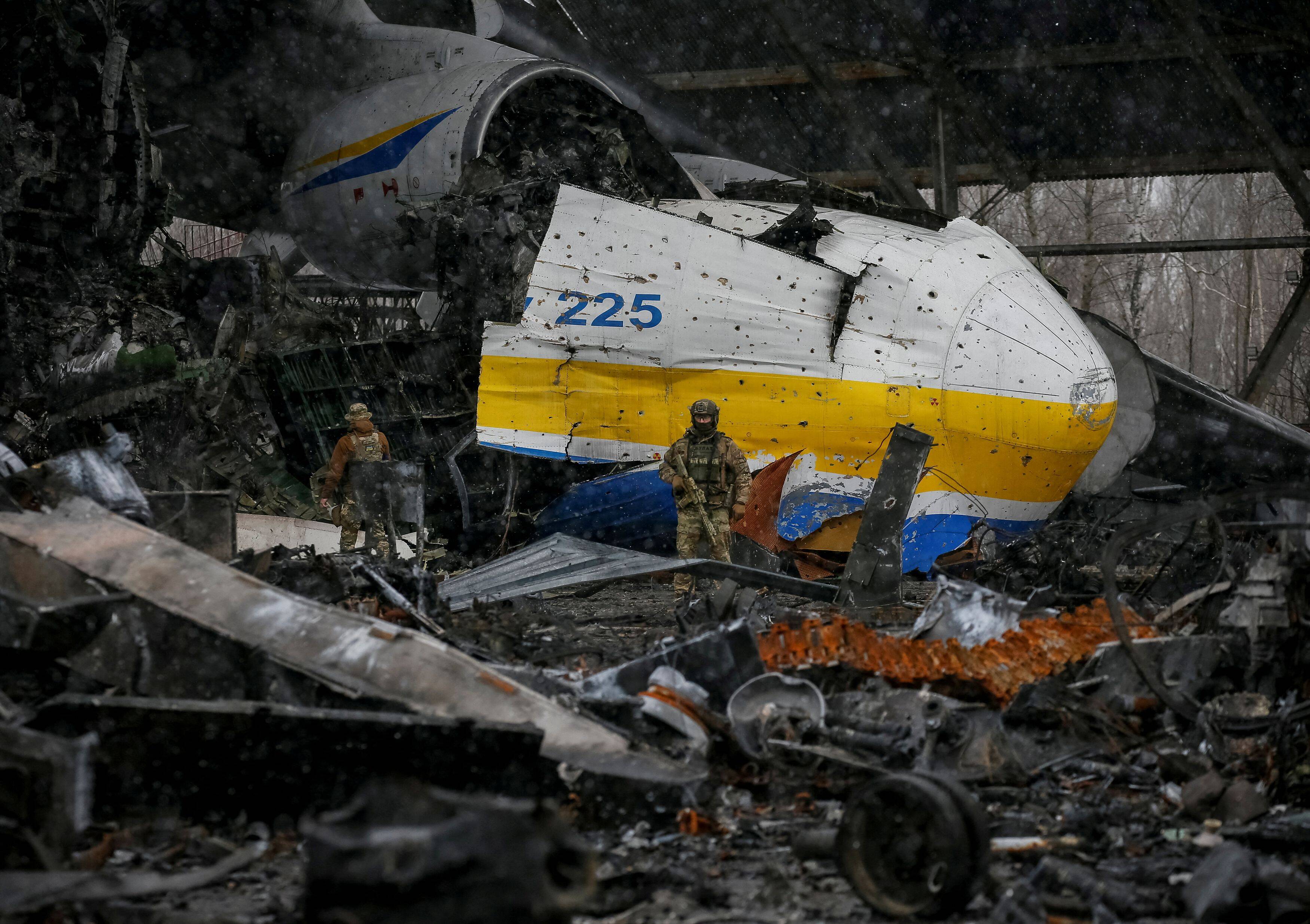 A Ukrainian service member stands in front of an Antonov An-225 Mriya cargo plane destroyed by Russian troops in Hostomel, Ukraine, on April 3. (Gleb Garanich/Reuters)