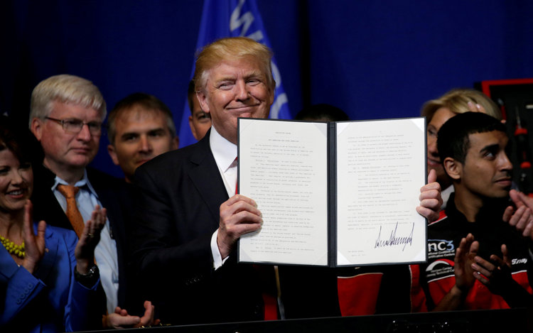 Trump smiles after signing an executive order. (Reuters/Kevin Lamarque)  