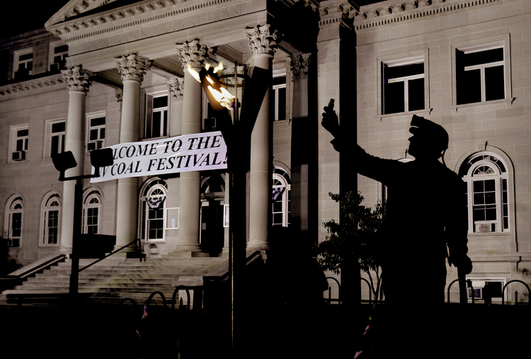 A statue honoring coal miners is seen in front of the Boone Courthouse, along with a memorial flame that stays list during the week-long Coal Festival. (Michael S. Williamson/The Washington Post)  
