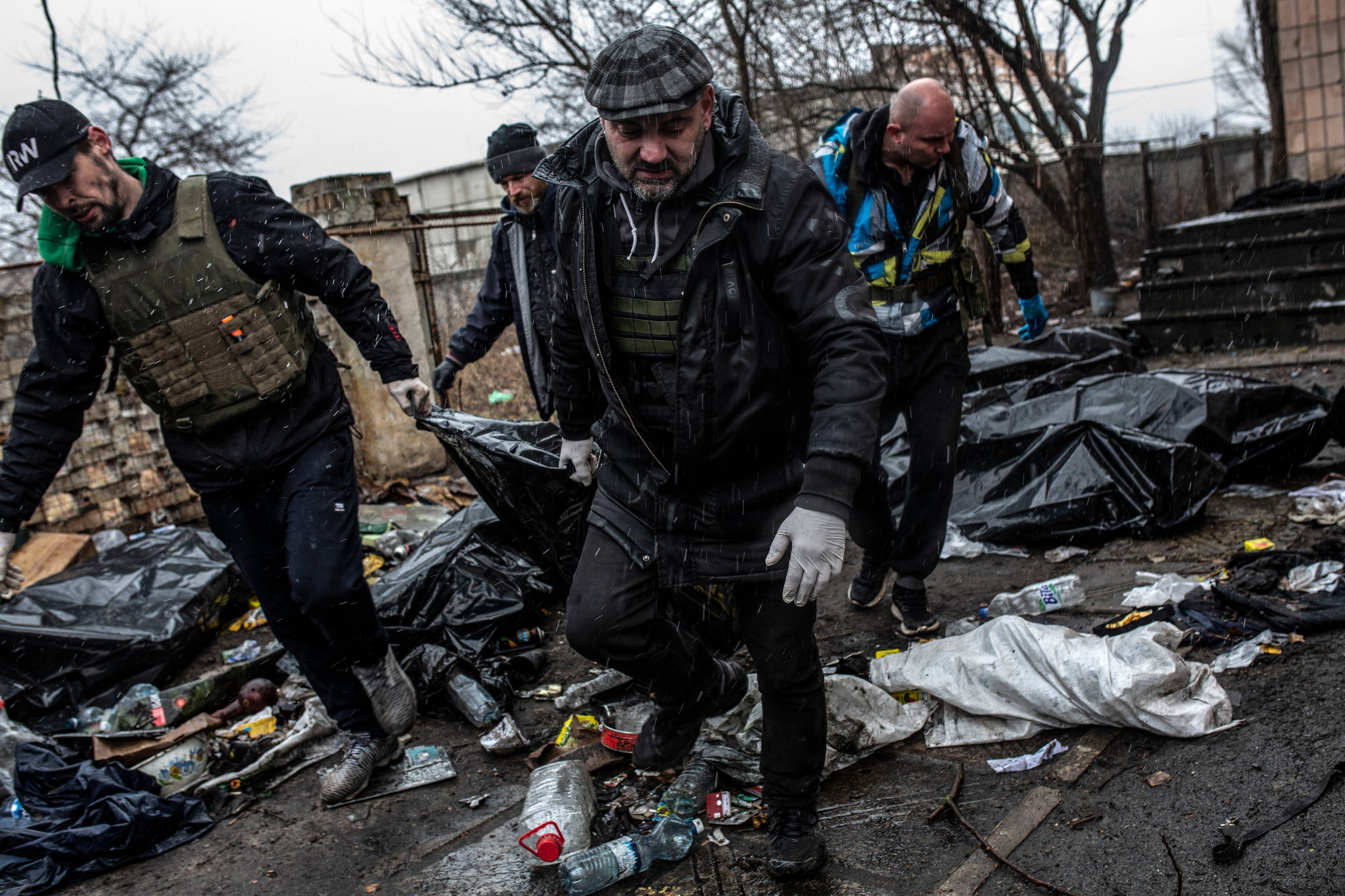 Volunteers carry away one of the bodies of the eight civilian men, two had their hands bonded together behind their backs, in Bucha, Ukraine on April 3. (Heidi Levine for The Washington Post)