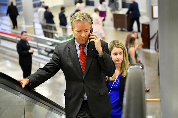Rand Paul talks on his cellphone while walking past throngs of reporters on Capitol Hill. (Katherine Frey/The Washington Post)  