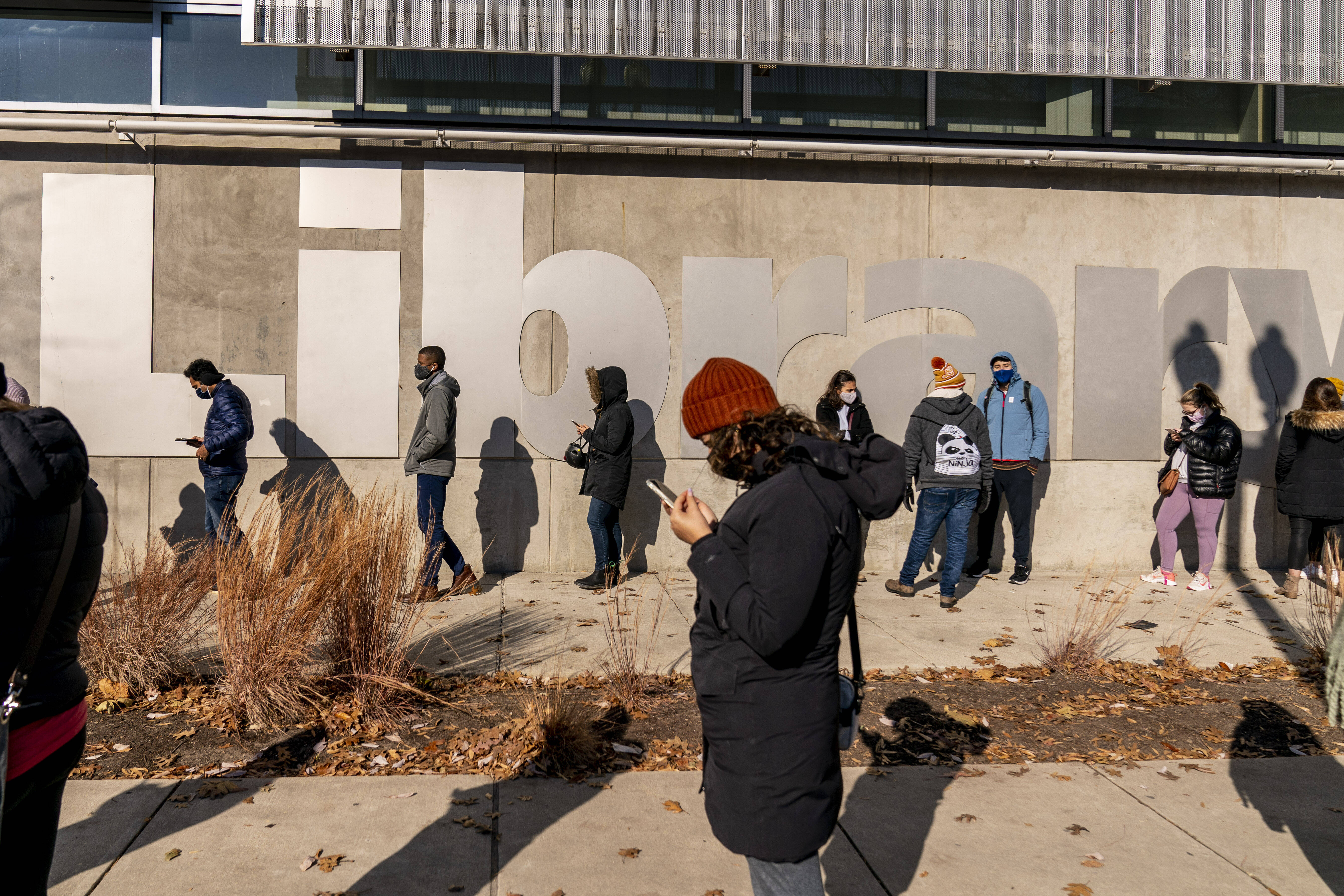 People wait for at-home coronavirus test kits in a long line that snakes around the Shaw Library in Washington on Dec. 22. (Andrew Harnik/AP)