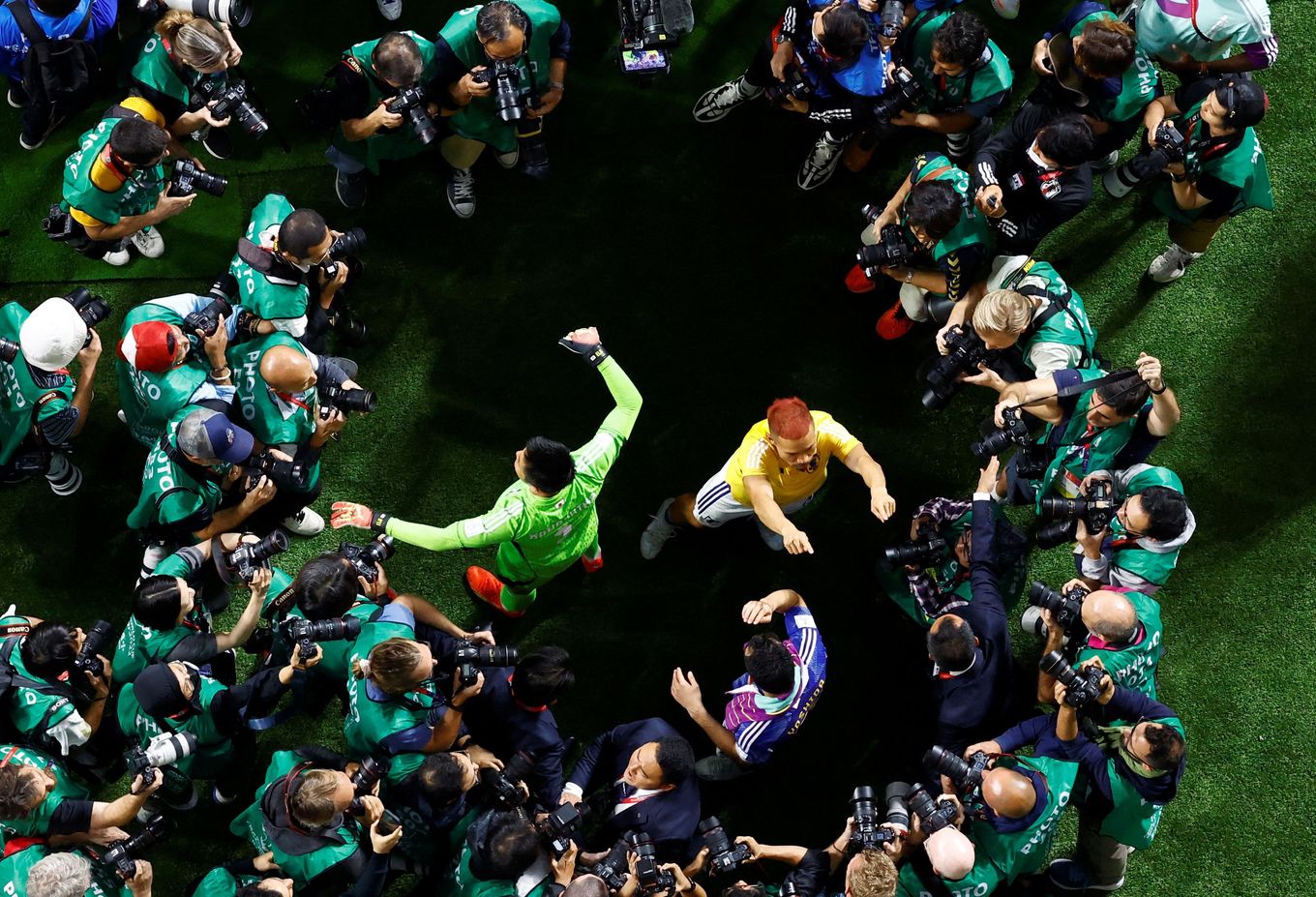 Japan's players are surrounded by photographers as they celebrate after qualifying for the knockout stages. (Peter Cziborra/Reuters)