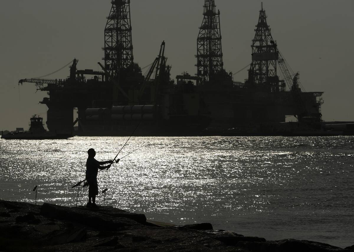A man fishes near drilling platforms in Port Aransas, Tex., on May 8, 2020. (Eric Gay/AP)