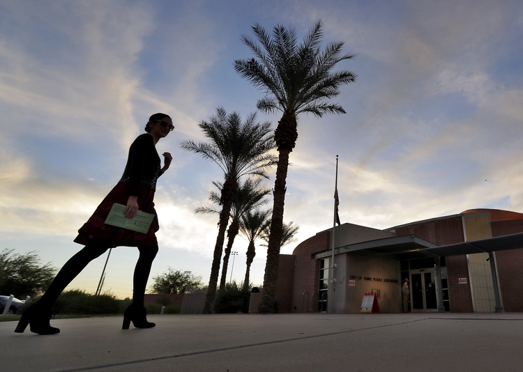 A voter carries in her mail in ballot to her polling station early this morning. (Matt York/AP)</p>  