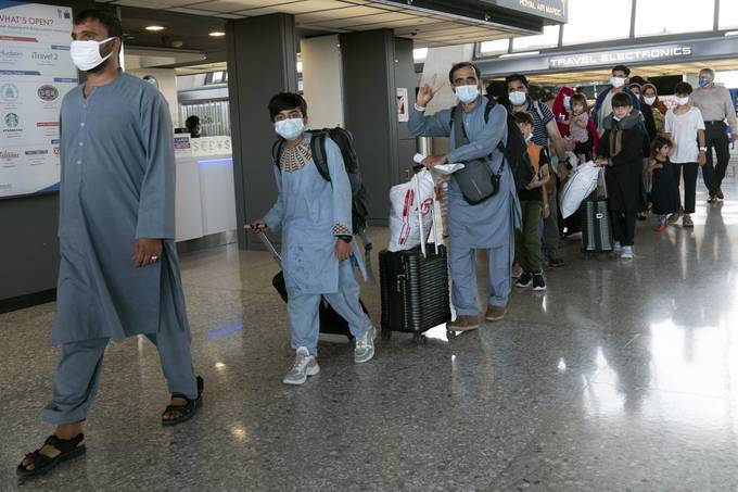 Families evacuated from Kabul walk through a terminal at Washington Dulles International Airport before boarding a bus on Aug. 23. (Jose Luis Magana/AP)