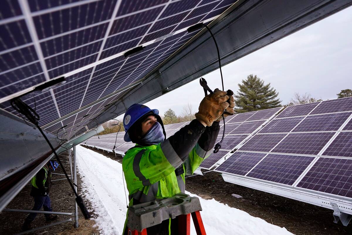 An electrician works on wiring solar panels in Oxford, Maine. (Robert F. Bukaty/AP)