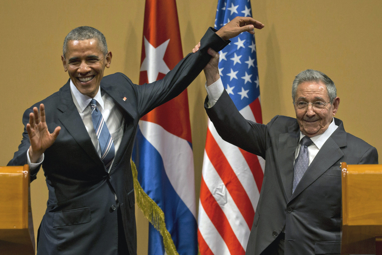 Cuban President Raul Castro tries to lift up Obama's arm at the conclusion of their joint news conference last year in Havana. (Ramon Espinosa/AP)</p>  
