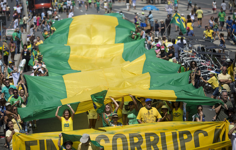 People hold a flag with the national colors of Brazil during a protest against corruption at Copacabana beach in Rio de Janeiro. (Silvia Izquierdo/AP)</p>