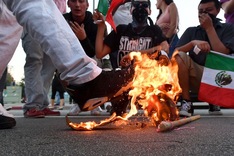 A Trump hat burns during a protest outside a Trump rally in San Jose. (Josh Edelson/Getty)</p>  