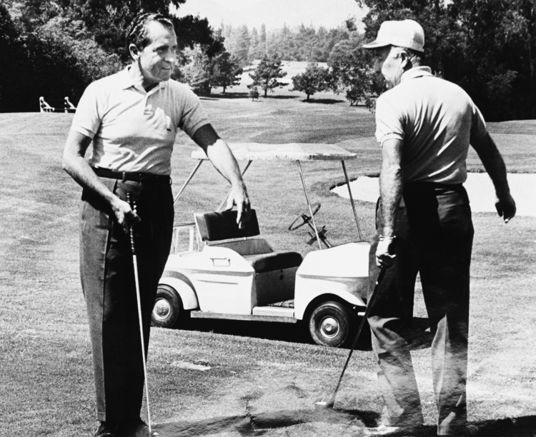 Attorney General John Mitchell steps aside to permit President Richard Nixon to tee off during a 1969 golf game at a country club in Los Angeles. (Harvey Georges/AP)</p>  