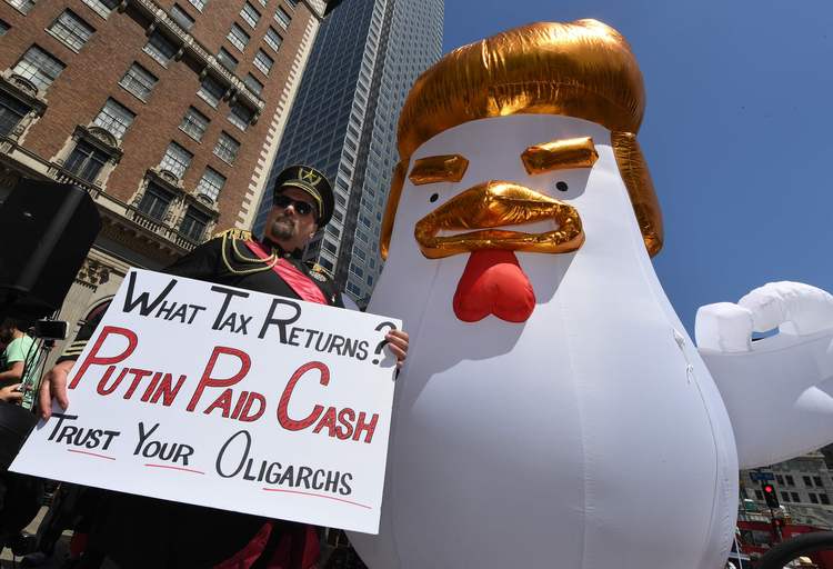 A man dressed as a Russian general stands beside a giant Trump chicken at a "Tax Day" march in Los Angeles. (AFP/Mark Ralston)</p>  