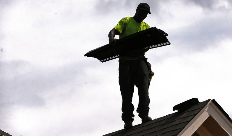 Larry McGee balances on the edge of a roof as he helps build a new house in a Brandon, Miss. (Rogelio V. Solis/AP)  