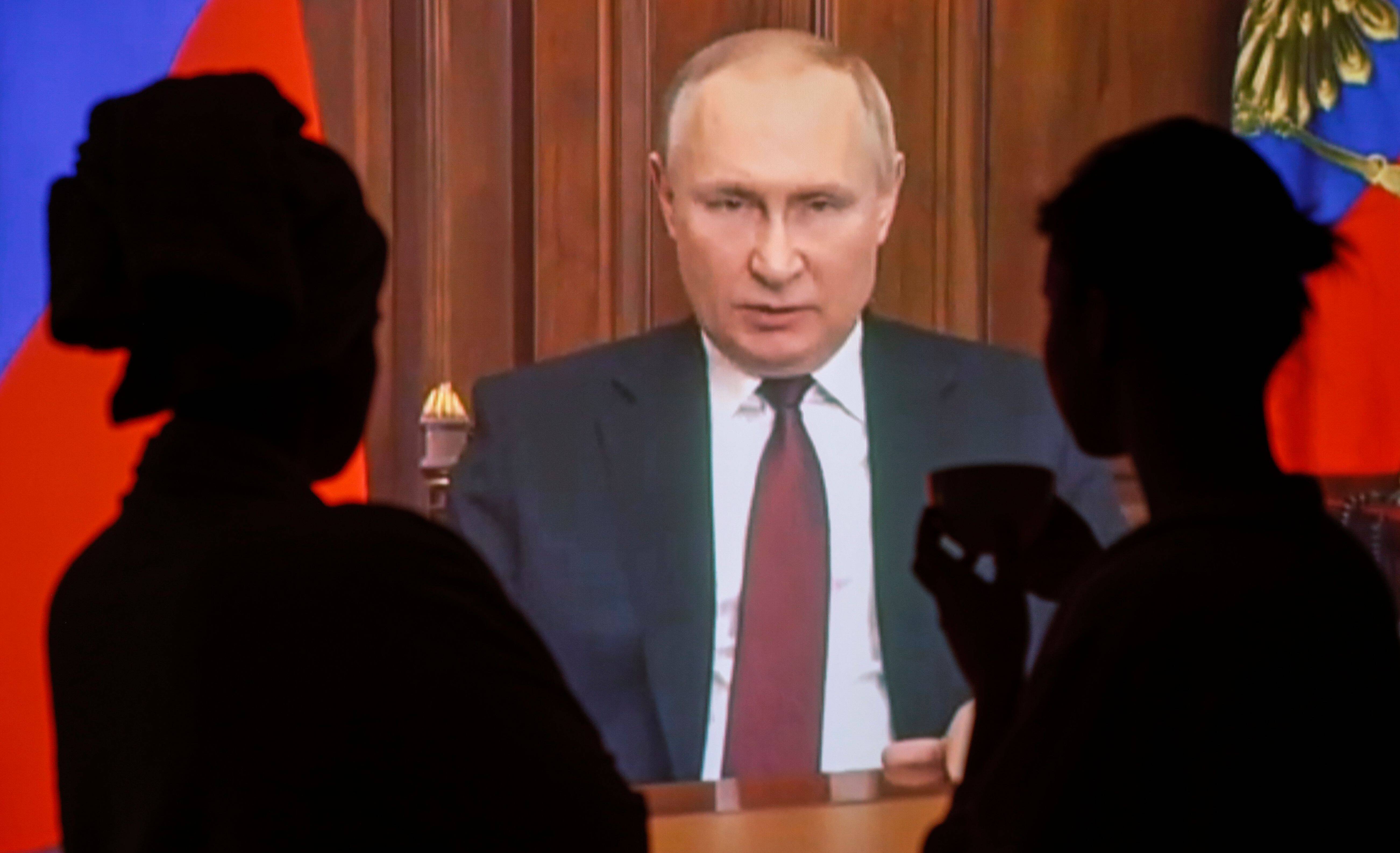 Russian people watch a special televised address by Russian President Vladimir Putin about authorizing a 