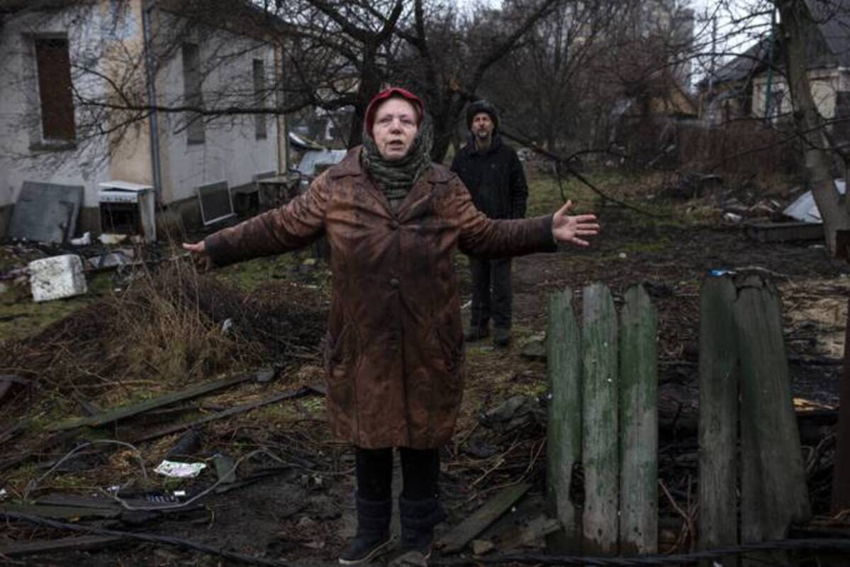 Larisa Savenko 72, stands outside her damaged home on Sunday with Andriy Leshbon in war torn Bucha, Ukraine, where destroyed Russian tanks, armored vehicles and other equipment litter the road where she lives. (Photo by Heidi Levine for The Washington Post).