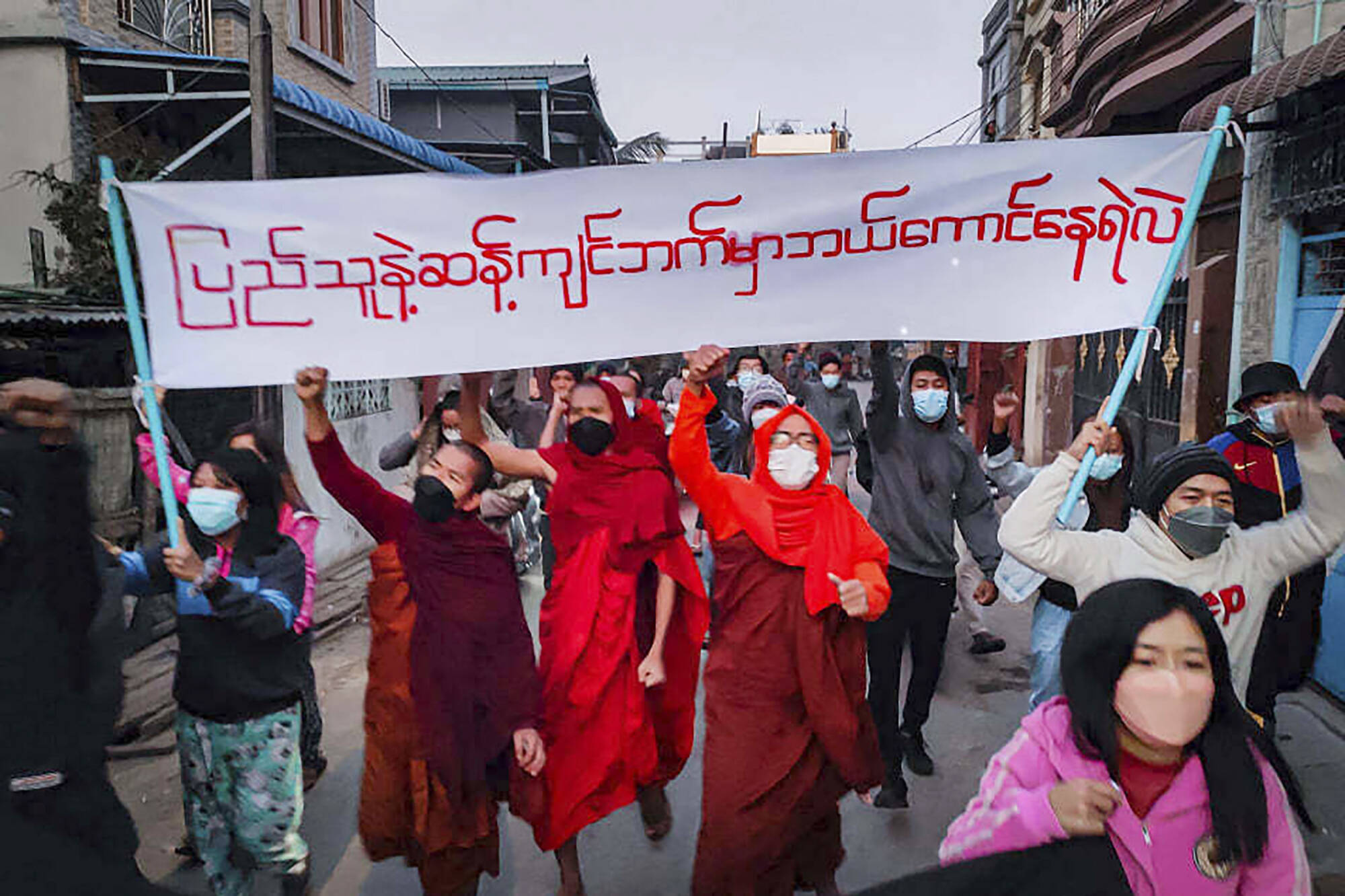 Youth activists and Buddhist monks participate in an anti-military government protest rally holding a banner that reads in Burmese, 