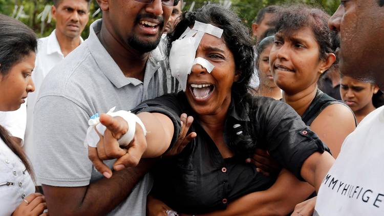 Kumari Fernando, who lost her husband and two children in the bombing at St. Sebastian's Church in Sri Lanka on Sunday, yells toward the graves during a mass burial for victims yesterday at a cemetery near the church in Negombo. (Thomas Peter/Reuters)  