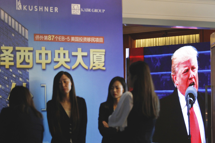 A projector shows Trump footage onscreen, as workers wait at an event promoting EB-5 in China. (AP)</p>