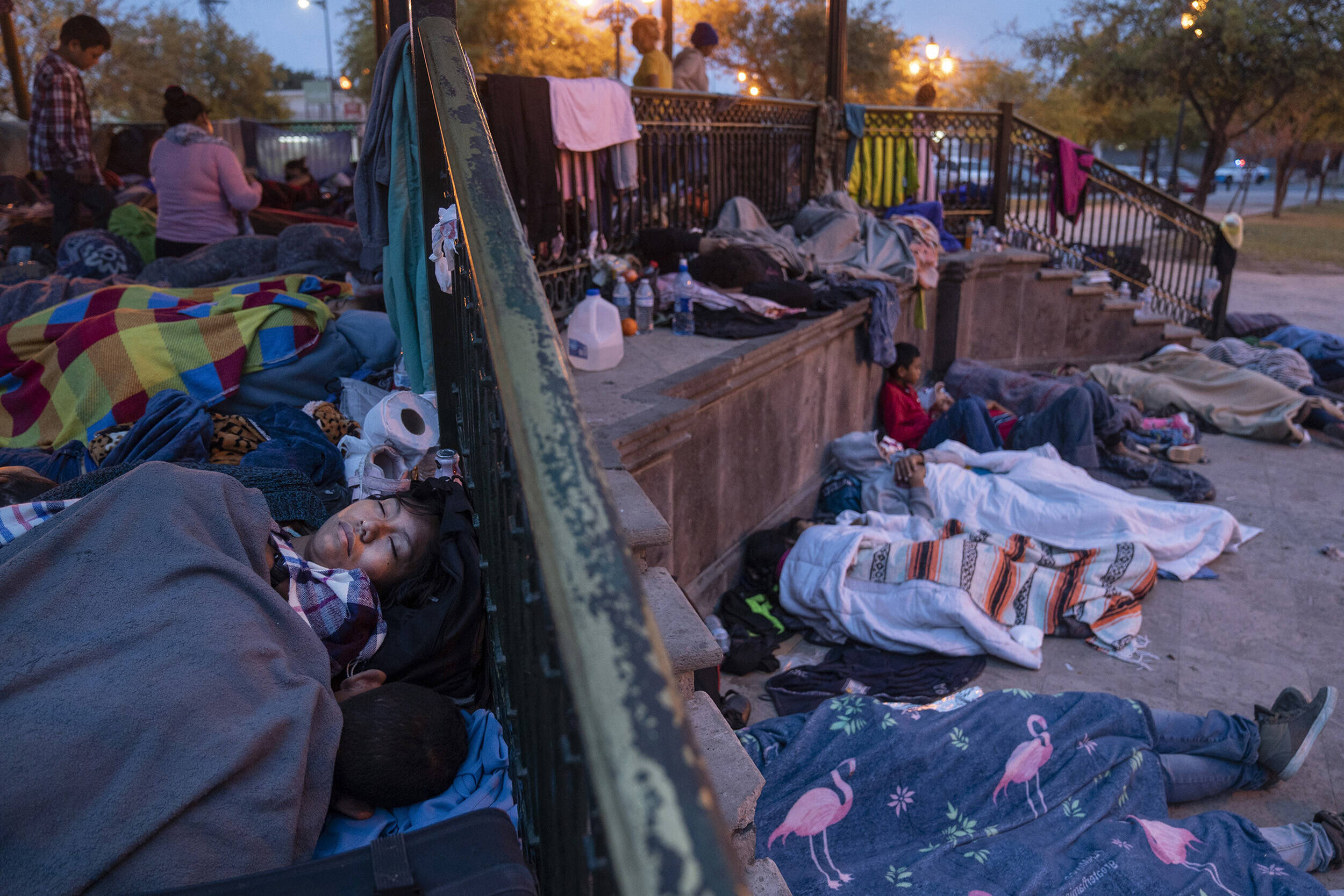 Recently deported immigrants, mostly from Central America, sleep under a gazebo near a border crossing into the U.S. Large numbers of immigrants, including young women and children, are crossing the border. (Michael Robinson Chavez/The Washington Post)