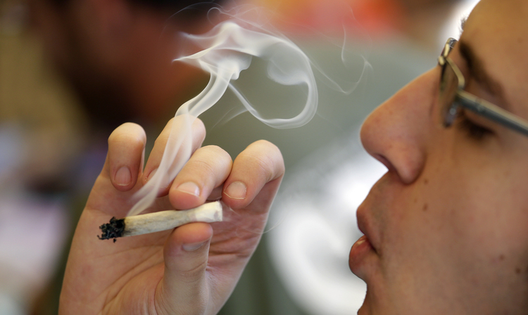 A Seattle&nbsp;man smokes a joint at a party celebrating weed on April 20.&nbsp;(AP Photo/Elaine Thompson)</p>  