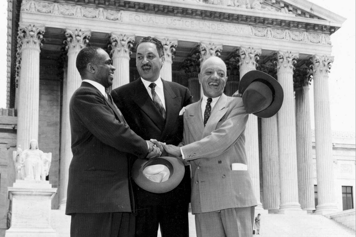 George E.C. Hayes, from left, Thurgood Marshall and James M. Nabrit join hands as they pose outside the Supreme Court in Washington on May 17, 1954. (AP Photo, File)