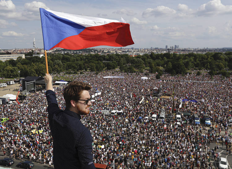 A man waves the Czech flag as people protest in Prague on June 23. (Petr David Josek/AP)  
