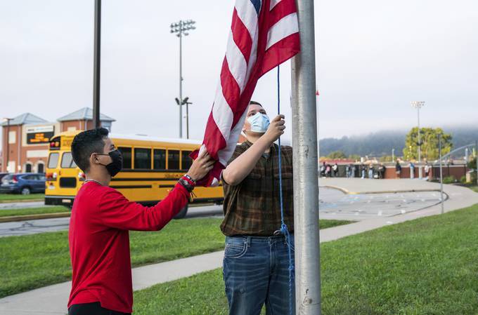 Students raise the flag outside Ambridge Area Senior High School on the first day of Pennsylvania's mask mandate for K-12 schools and day care centers. (Andrew Rush /Pittsburgh Post-Gazette via AP)