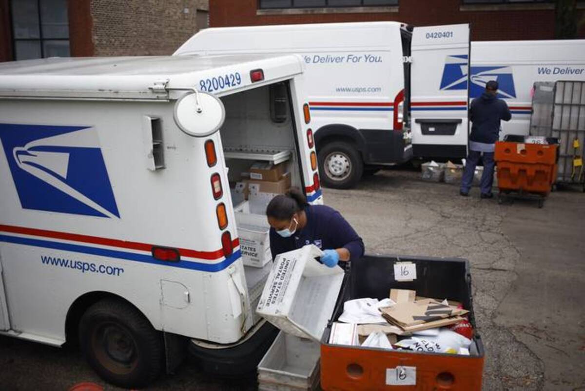 Workers load mail into delivery vehicles outside a U.S. Postal Service distribution center in Chicago. (Luke Sharrett/Bloomberg News)&nbsp;