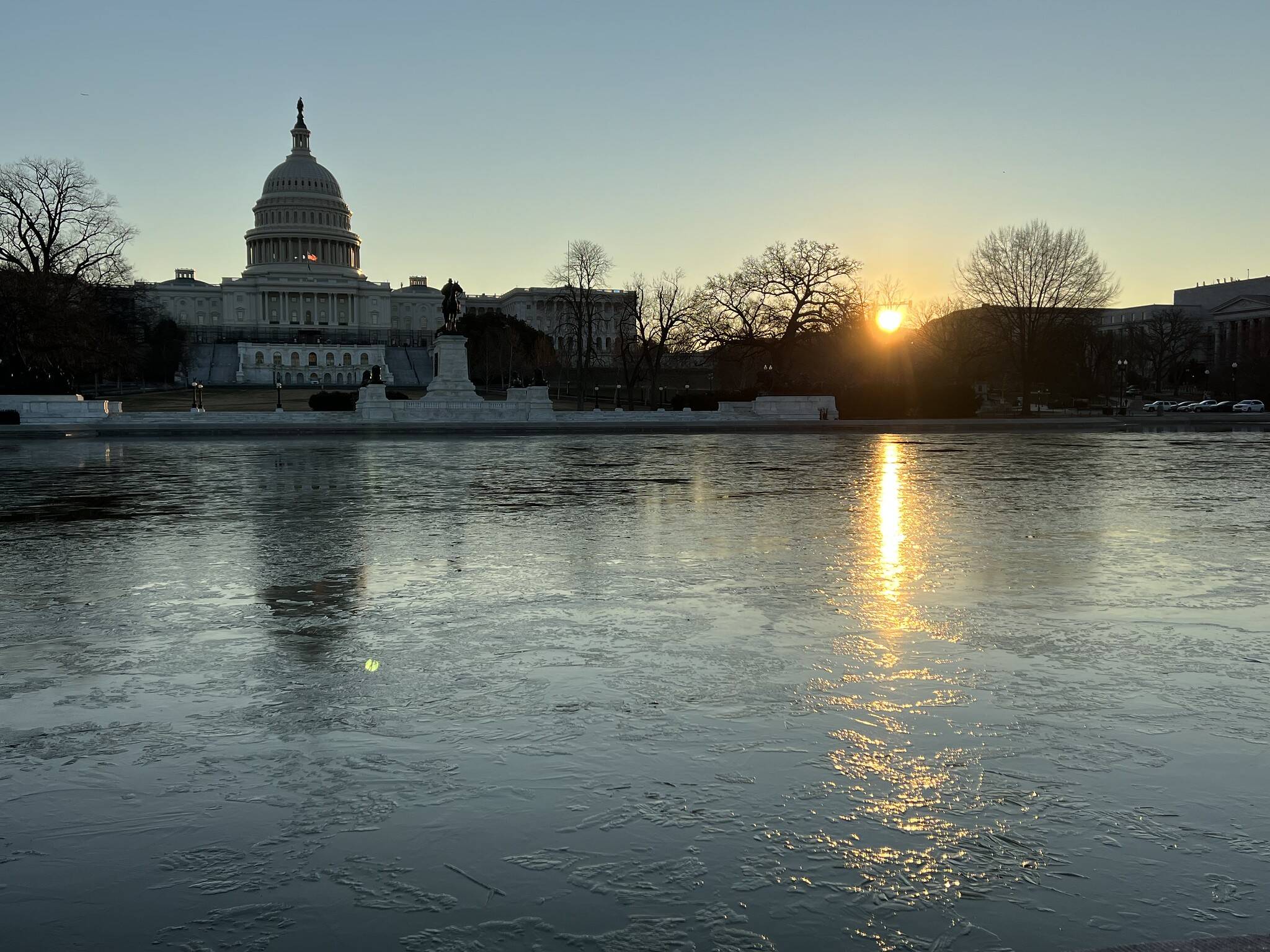 Blue sky on Wednesday over icy Reflecting Pool at the Capitol as sun rises Wednesday.