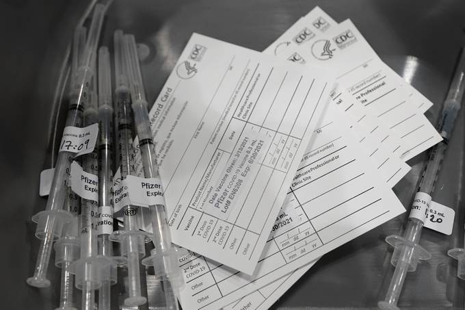 Syringes with doses of the Pfizer coronavirus vaccine are shown next to vaccination cards at the Lumen Field Events Center in Seattle on March 13. (Ted S. Warren/AP)