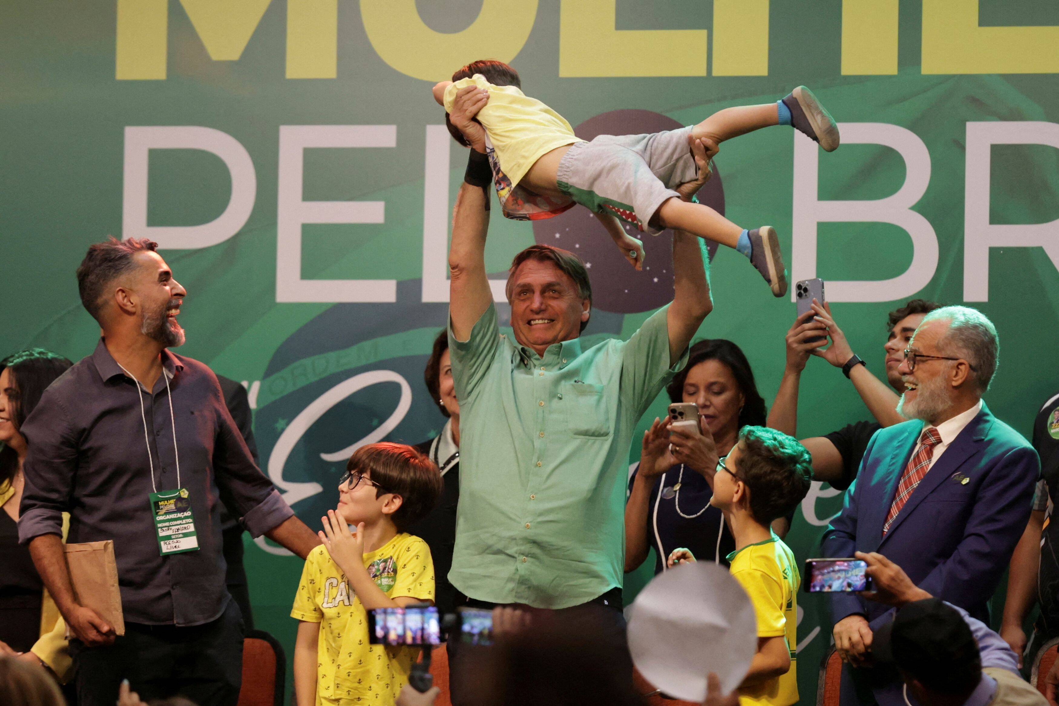 Brazil President Jair Bolsonaro lifts a boy during an event in Contagem in Minas Gerais state, Brazil, on Sept. 23. (Cristiane Mattos/Reuters)