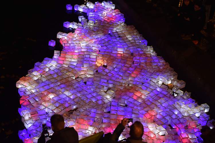 People take photos of lanterns set afloat in the Canal Saint-Martin in Paris yesterday on the one-year anniversary of the terror attack that killed 130. (Alain Jocard/AFP/Getty Images)</p>  