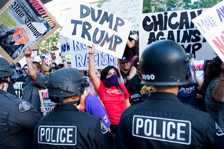 Police form a line to contain protesters outside a San Jose rally. (AP/Noah Berger)</p>  