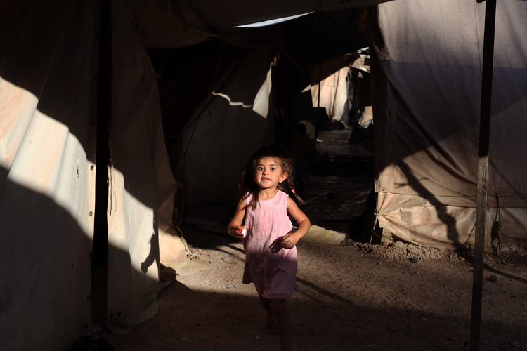A little girl runs among tents as she plays with other children at a&nbsp;refugee camp in Athens yesterday. (Petros Giannakouris/AP)</p>  