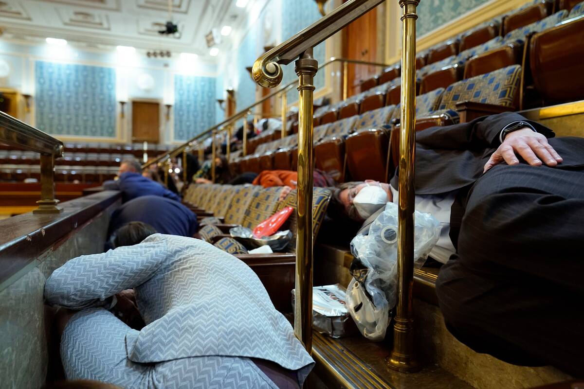 People shelter in the House gallery as protesters try to break into the House Chamber at the U.S. Capitol on Wednesday, Jan. 6, 2021. (Andrew Harnik/AP Photo)
