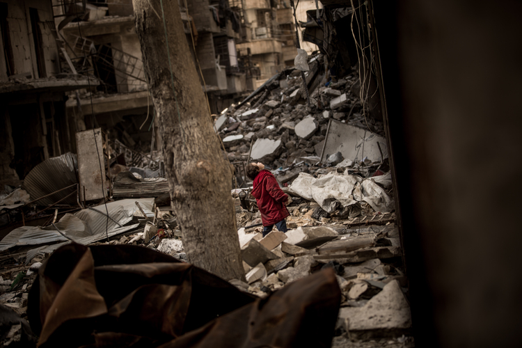 In a destroyed alley in East Aleppo, a little girl stands in the rubble and looks for fighter jets in the sky above. (Christian Werner/Zeitenspiegel)  