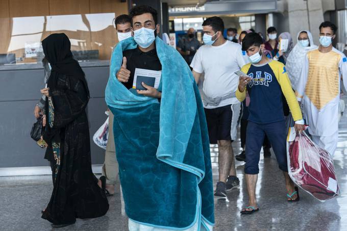 People evacuated from Kabul walk through a terminal at Washington Dulles International Airport before boarding a bus on Aug. 25. (Jose Luis Magana/AP)