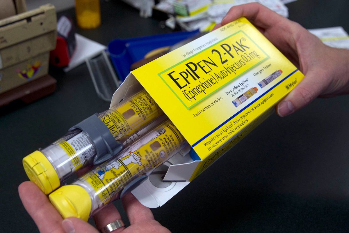 A pharmacist holds a package of EpiPens epinephrine auto-injector, a Mylan product, in Sacramento, Calif., March 24, 2020, (AP Photo/Rich Pedroncelli)