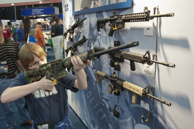 A&nbsp;young man checks out merchandise at the&nbsp;National Rifle Association's&nbsp;annual convention.&nbsp;(AP File&nbsp;Photo/Steve Ueckert)</p>  