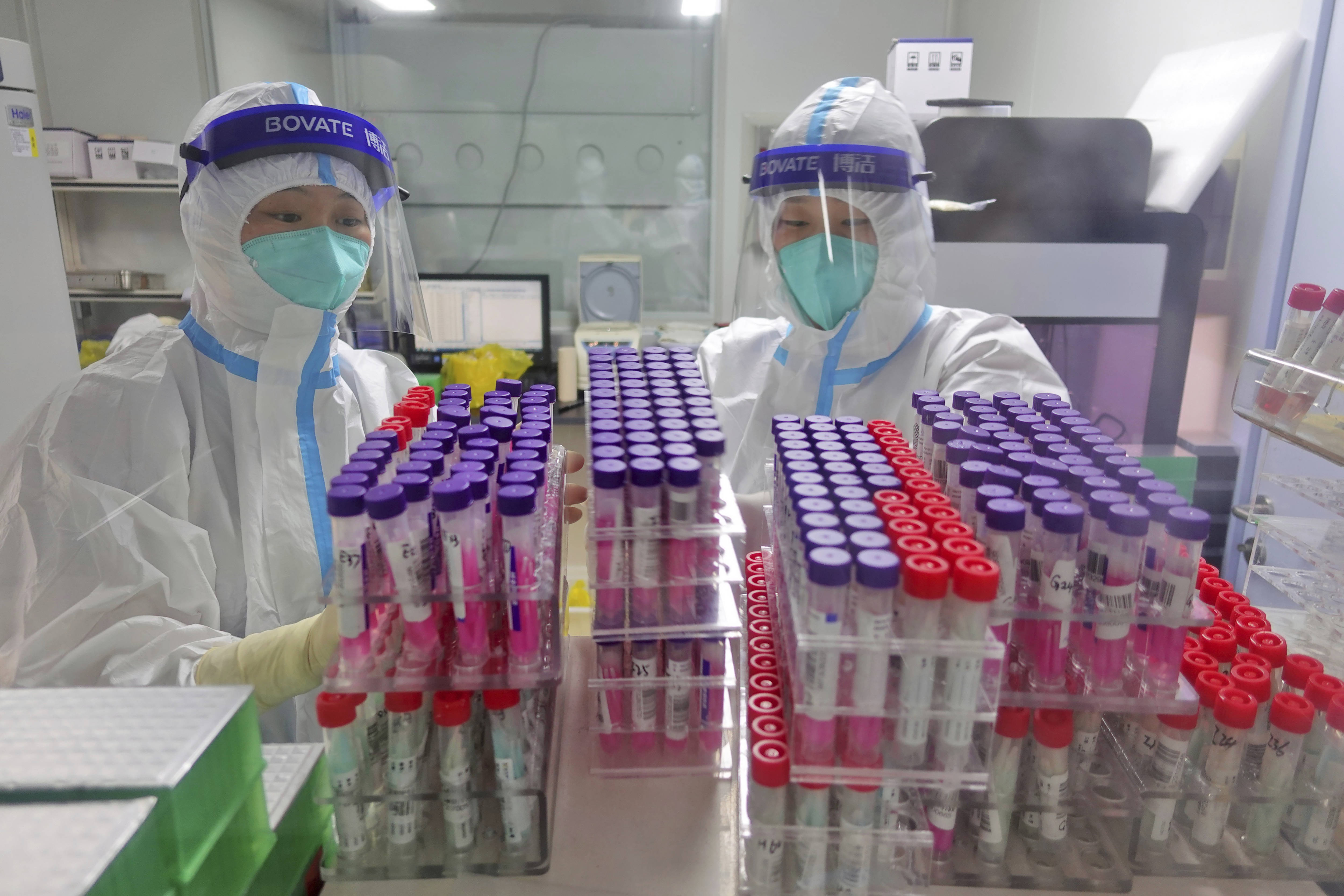 Workers handle swab samples for coronavirus in China, where the virus originated. (Chinatopix via AP)