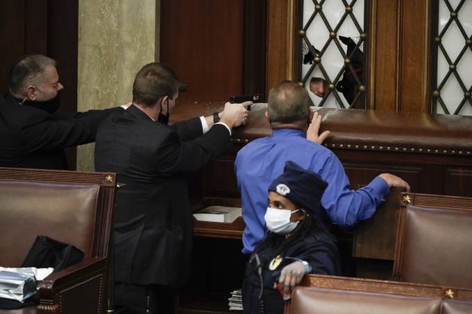 U.S. Capitol Police officers, with guns drawn, and Rep. Troy Nehls (R-Tex.) attempt to barricade House chamber doors during the riot on Jan. 6.&nbsp;