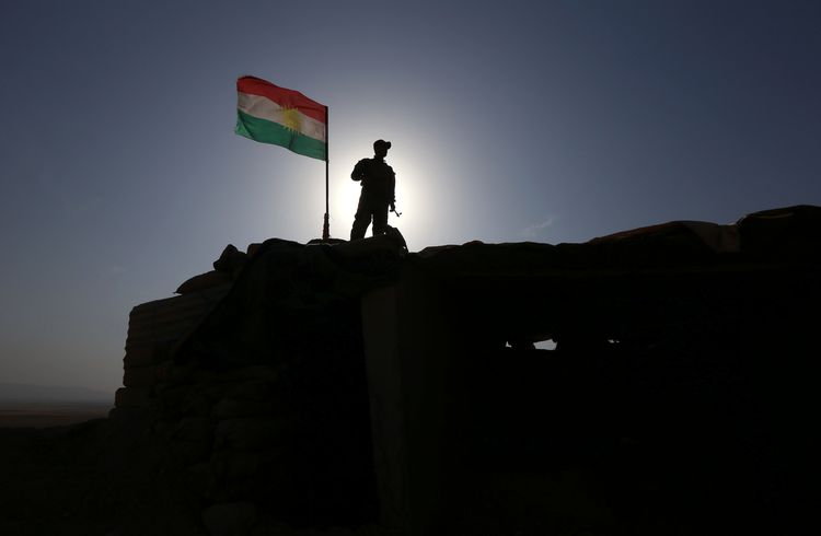 An Iraqi Kurdish Peshmerga fighter, next to a Kurdish flag, holds a position in a village near the town of Bashiqa, 25 clicks northeast of Mosul, yesterday. The operation to reclaim Mosul&nbsp;from ISIS continues. (Safin Hamed/AFP/Getty Images)</p>  