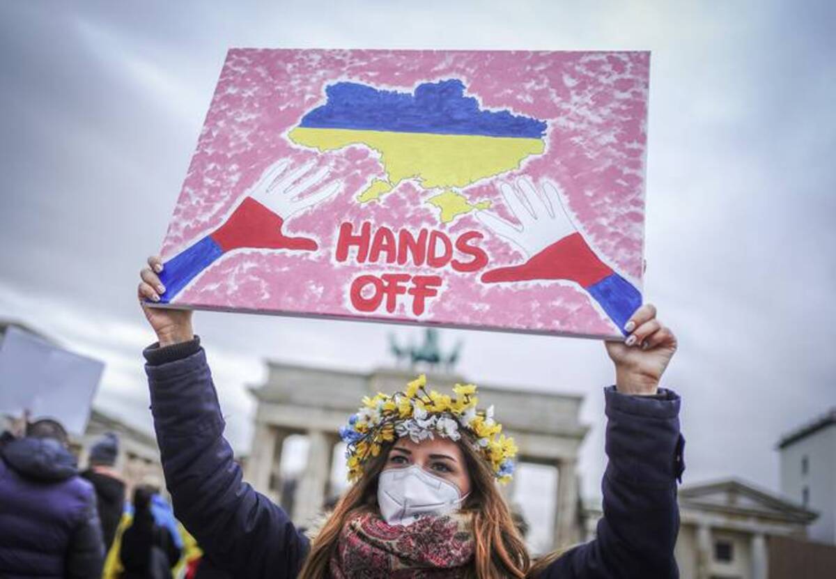 A woman holds a banner during a demonstration in Berlin following the Russian attack of Ukraine this morning. (Kay Nietfeld/dpa via AP)