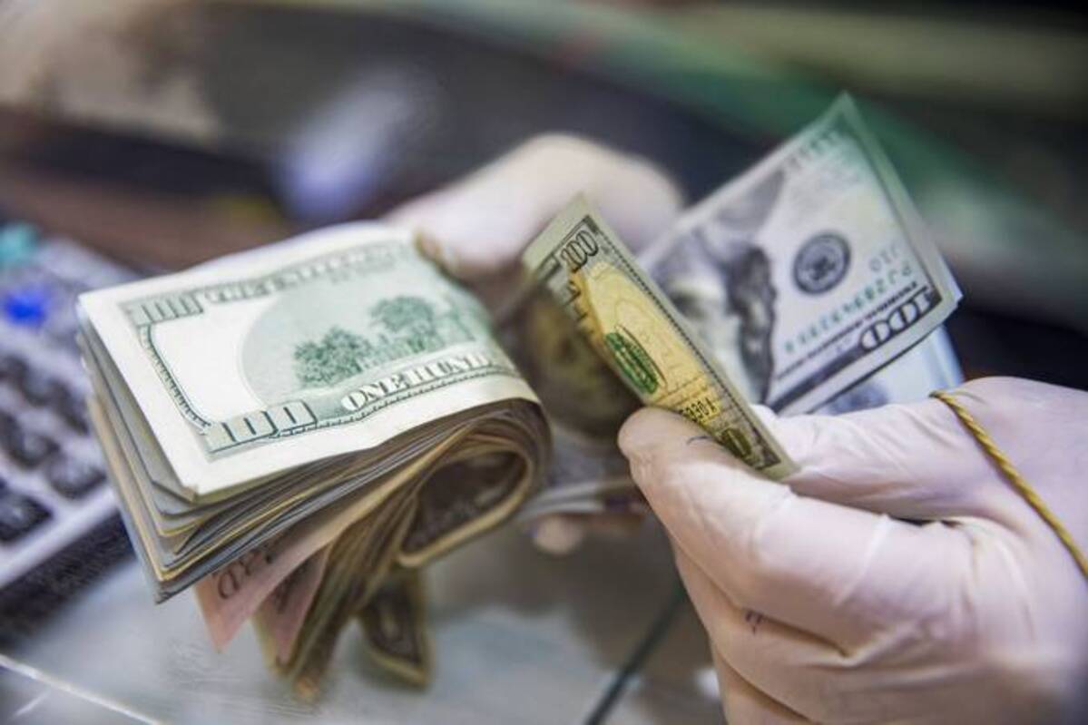 A worker wearing protective gloves counts U.S. dollar bank notes at a currency exchange kiosk. (Francesca Volpi/Bloomberg News)