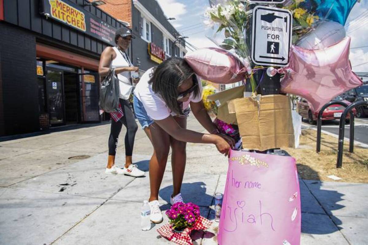 Shante Williams, 26, and Tamika Smith, 26, left, put down candles and a sign to give their condolences for a memorial for the shooting death of 6-year-old Nyiah Courtney, who was killed on the night of July 16. (Michael Blackshire/The Washington Post)