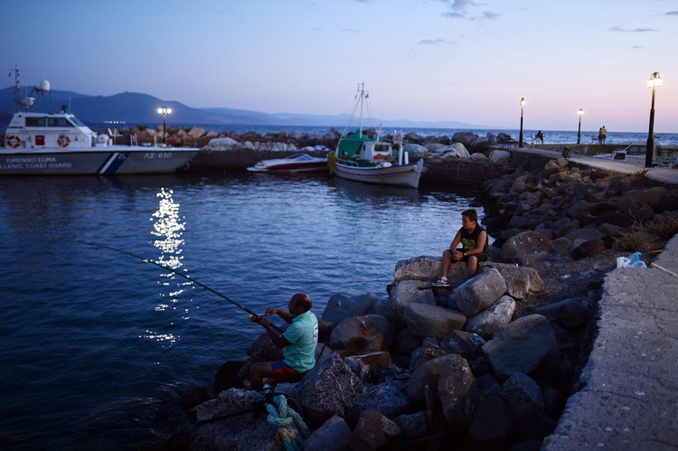 A man fishes in the normally bustling port village of Molyvos on the island of Lesbos. (AFP/Louisa Gouliamaki)</p>  