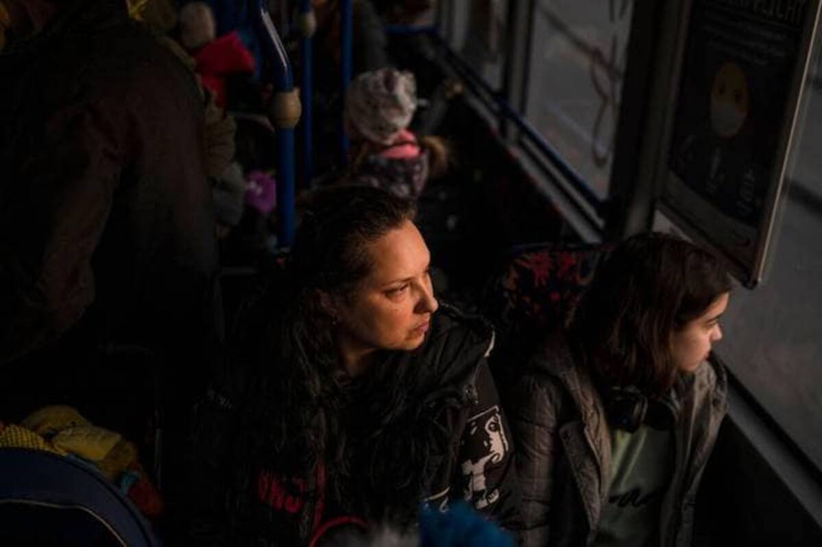 Ukrainian evacuees sit on a shuttle bus transporting refugees, after crossing the Ukrainian border with Poland at the Medyka border crossing on Monday. (Photo by Angelos Tzortzinis / AFP)