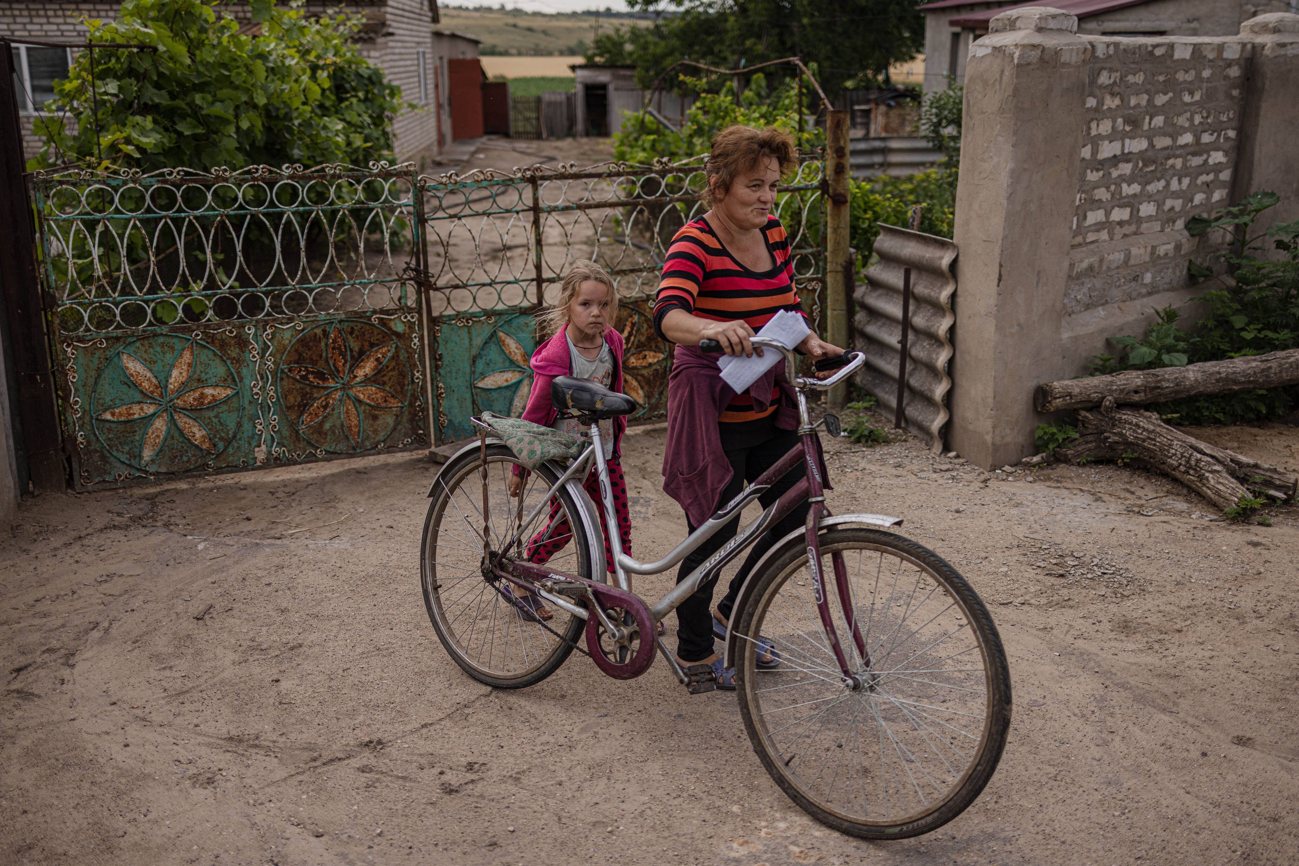 Alyona Kharaim and her daughter leave their house to get fresh milk. (Serhiy Morgunov for The Washington Post)