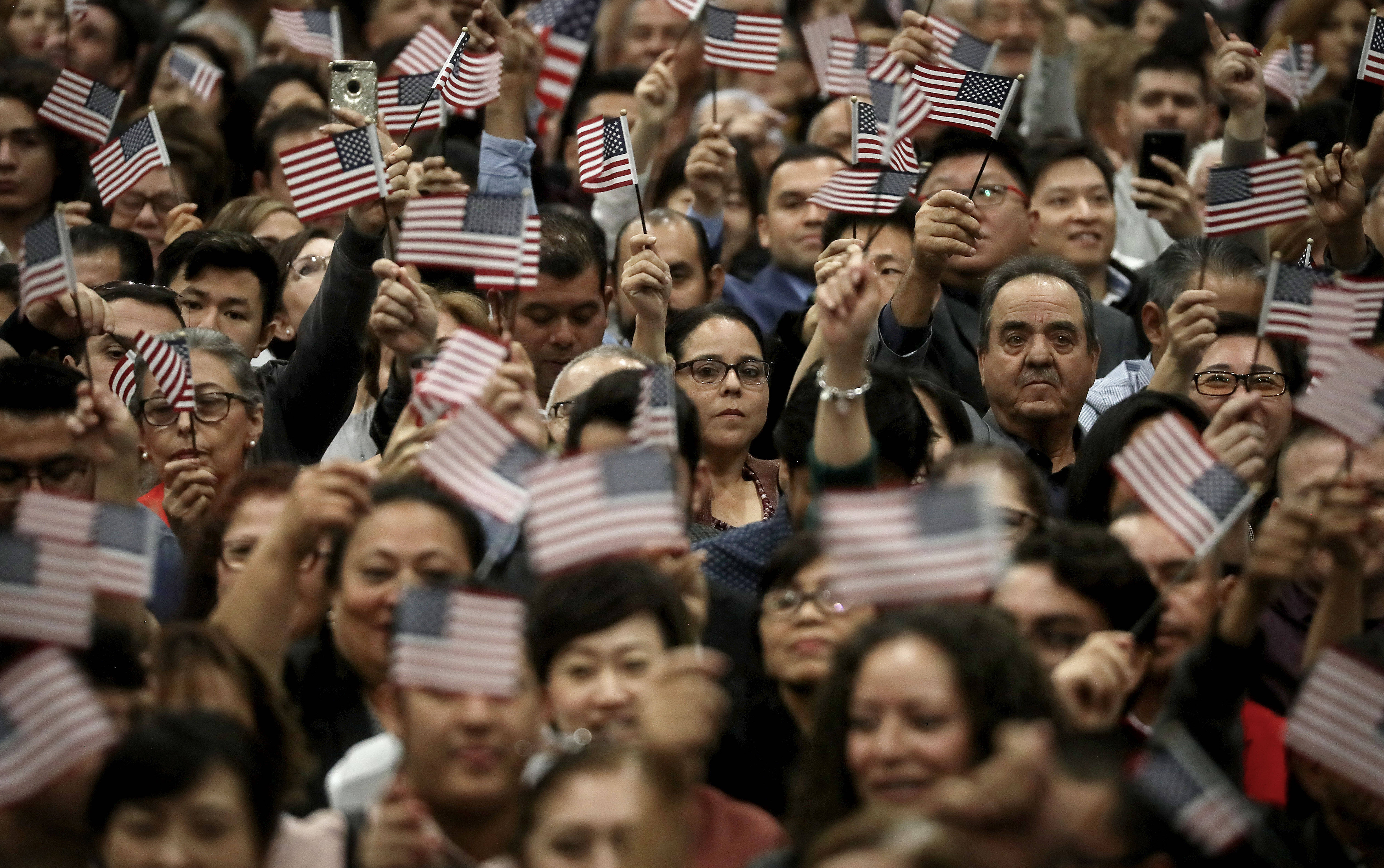 New U.S. citizens wave American flags during a naturalization ceremony in 2018 in Los Angeles. (Mario Tama/Getty Images)