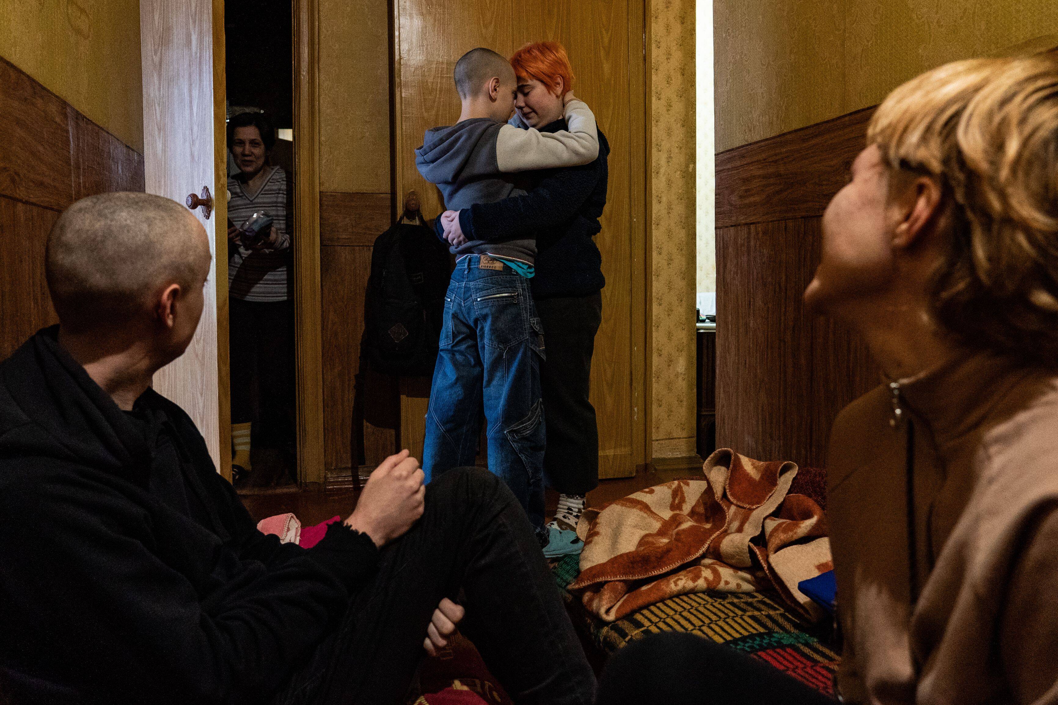 Eugene, 37, sits in a hallway of his apartment with his girlfriend Alina, 24, as his son Seva, 12, hugs his cousin Anya, 18, in the background in Dnipro, Ukraine on March 2. (Salwan Georges/The Washington Post)